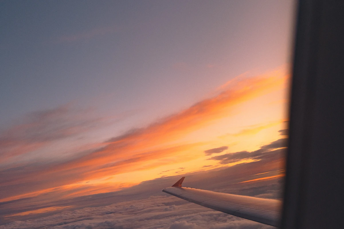 Sunset above the clouds seen past an aircraft wing